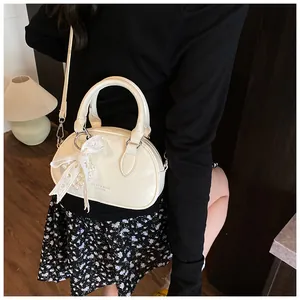 Detail of cream bowling bag featuring lace bow, pearl charm and silver hardware