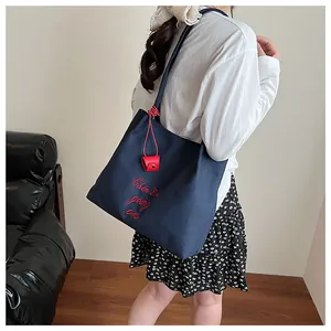 Vue détaillée du sac cabas en toile bleu marine avec broderie rouge et accessoire décoratif