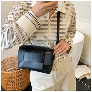 Moderna borsa a tracolla nera con patta in morbida ecopelle in un contesto lifestyle