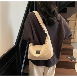 Dettaglio borsa a mezzaluna beige in nylon testurizzato con tracolla regolabile su modella