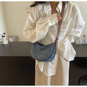 Dettaglio borsa a mezzaluna in denim con borchie argento e tracolla in pelle marrone