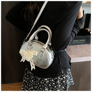 Detail of silver metallic pleated mini bag with pearl bow charm and shoulder strap