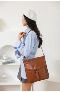 Borsa a tracolla vintage in pelle marrone con fibbia indossata a spalla da una modella