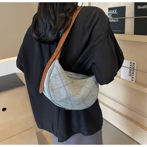 Dettaglio borsa a mezzaluna in denim con rivetti di strass e tracolla in pelle marrone