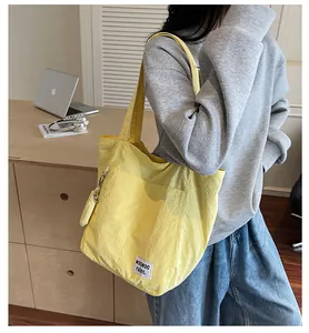 Détail du sac cabas en nylon jaune avec écusson lettré et pompon décoratif