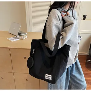 Détail du sac cabas en nylon noir avec étiquette de marque et mini pochette ronde