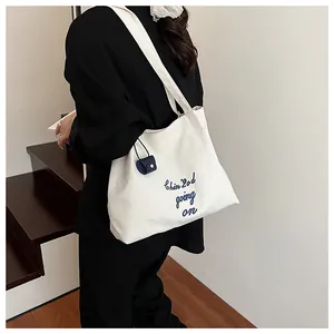 Détail du sac cabas en toile blanche avec broderie bleue et petit accessoire bouton