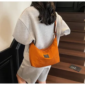 Borsa a tracolla a mezzaluna in nylon arancione abbinata a un completo casual grigio