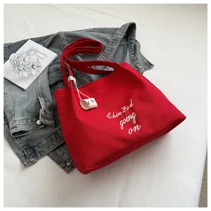 Détail d'un grand sac cabas en toile rouge avec broderie blanche dans un décor lifestyle