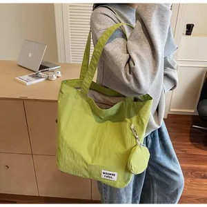 Détail du cabas en nylon vert avec un porte-monnaie rond et une étiquette tissée