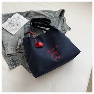 Gros plan du sac fourre-tout bleu marine avec broderie rouge et breloque en cœur