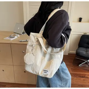 Détail du grand sac cabas crème montrant la texture plissée et la petite pochette