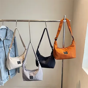 Borsa a tracolla a mezzaluna in nylon in quattro colori appesa a un supporto