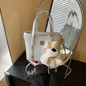 Chic silver metallic bucket bag with plush charm and shoulder strap for summer 2025