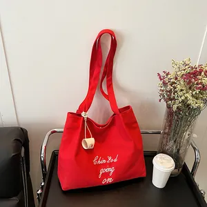 Grand sac cabas en toile rouge avec broderie blanche sur un chariot noir