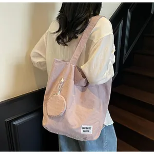 Détail du sac cabas en nylon lavande avec pochette ronde portée au dos par le mannequin