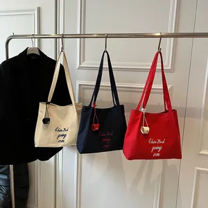 Grand sac cabas en toile brodé en crème, bleu marine et rouge suspendu sur un portant