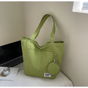 Grand sac fourre-tout vert clair avec petite pochette sur un bureau de travail