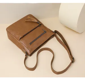 Dettaglio borsa a tracolla marrone con nappe vintage e tasche multiple con cerniera