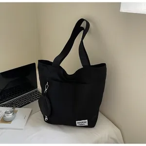 Détail du sac fourre-tout en toile noire avec poche latérale et petit porte-monnaie rond