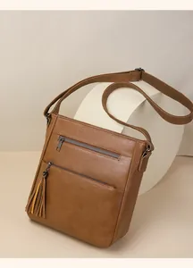Dettaglio della borsa a tracolla in ecopelle marrone con doppia zip frontale e nappa