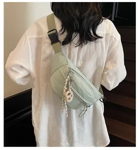 Detail of mint green crossbody bag featuring water-resistant fabric and woven zipper pulls