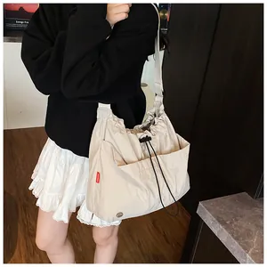 Dettaglio della borsa a secchiello in nylon beige con coulisse e tasca frontale su modella