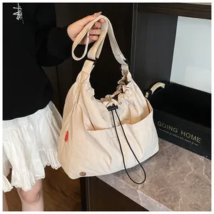 Dettaglio borsa a secchiello in nylon beige con coulisse e tracolla regolabile