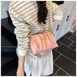 Close-up of pink pleated cloud bag with slim metal chain strap and glossy texture