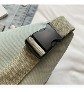 Detailed macro view of a durable black plastic buckle on a light green canvas strap