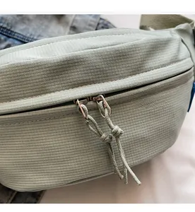 Close-up of dual zipper closure on light green textured fabric crossbody bag
