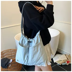 Dettaglio della borsa a secchiello in nylon azzurro con chiusura a coulisse e tasche frontali