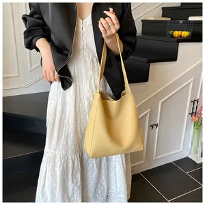 Dettaglio della borsa tote gialla con trama in pelle indossata da una modella elegante