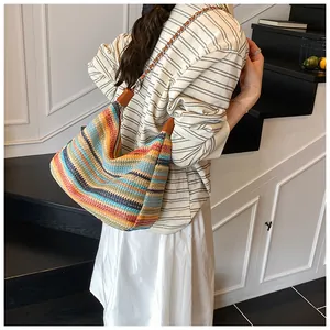 Detail of colorful rainbow woven straw tote bag with chain strap on model's shoulder