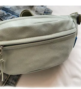 Macro view of sage green corduroy chest bag featuring textured fabric and zipper details