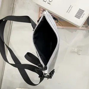 Borsa a tracolla sportiva argento metallizzato con tracolla in nylon nero su tavolo