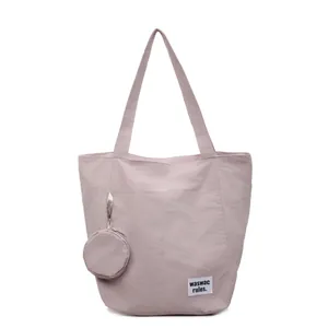 Sac cabas en toile rose avec porte-monnaie rond et étiquette sur fond blanc