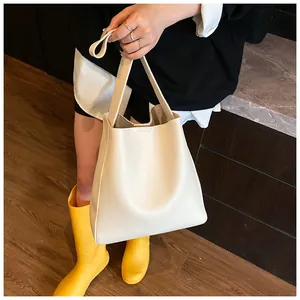 Dettaglio della borsa tote bianco crema in pelle martellata con nodi decorativi sui manici