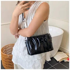 Detail of black pleated cloud bag with glossy finish and silver metal hardware