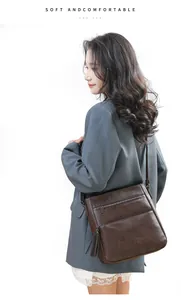 Dettaglio borsa a tracolla in pelle marrone scuro con cerniere multiple e nappa decorativa