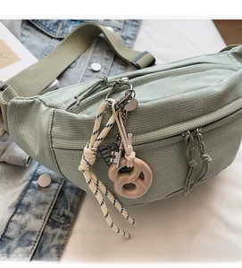 Detail of mint green corduroy chest bag with zipper and unique pretzel keychain ornament