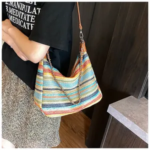 Close-up of colorful rainbow straw woven tote bag with metallic chain and leather straps