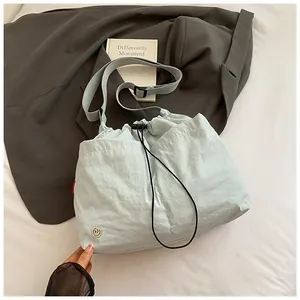 Dettaglio borsa a secchiello in nylon azzurro con chiusura a coulisse e logo in metallo