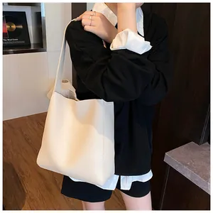 Dettaglio della borsa tote in pelle crema con trama a grana litchi e logo minimalista raffinato