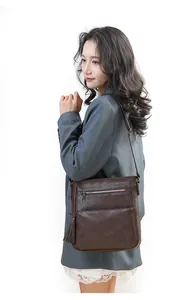 Dettaglio borsa a tracolla vintage marrone con tasche a zip e nappina decorativa raffinata