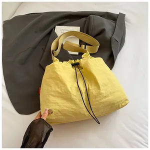 Dettaglio della borsa a secchiello in nylon giallo con coulisse e texture increspata