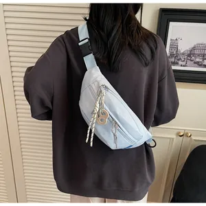 Rear view of light blue nylon crossbody bag with adjustable buckle and creative charms