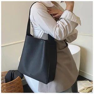 Dettaglio della borsa tote in pelle nera a grana con logo goffrato e base in metallo