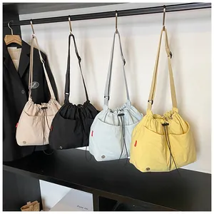 Selezione di borse a secchiello colorate in nylon con coulisse in beige, nero e giallo