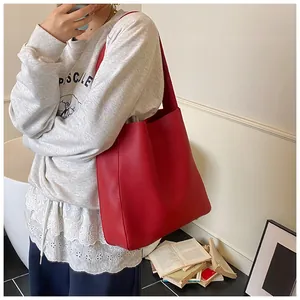 Grande borsa tote rossa in pelle con grana fine indossata a spalla da una modella